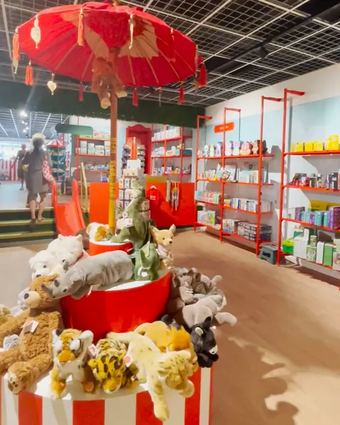 Een rood-wit gestreepte carrousel vol knuffels onder een rode parasol.